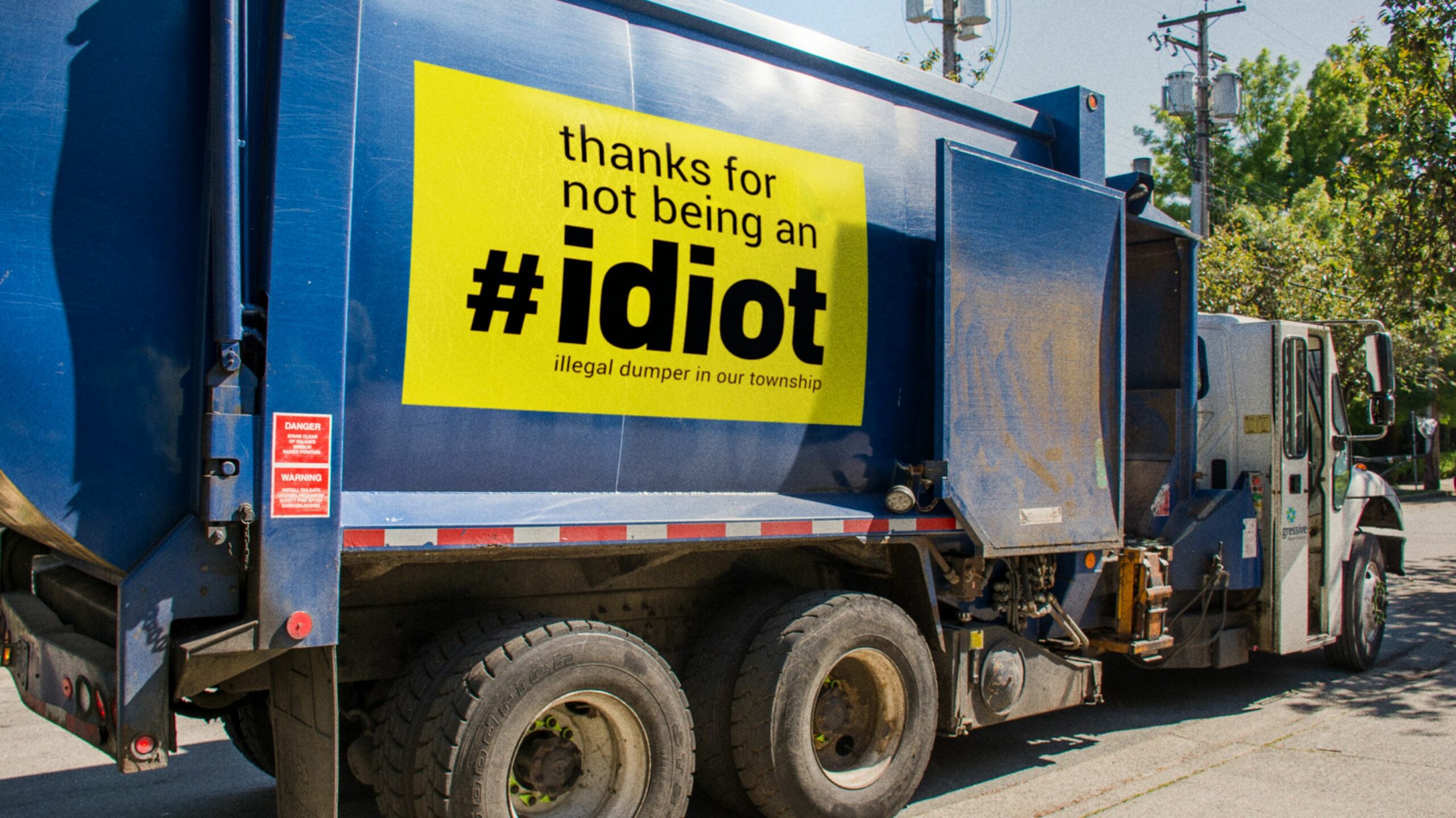 IDIOT: Illegal Dumper in Our Township ad on garbage truck